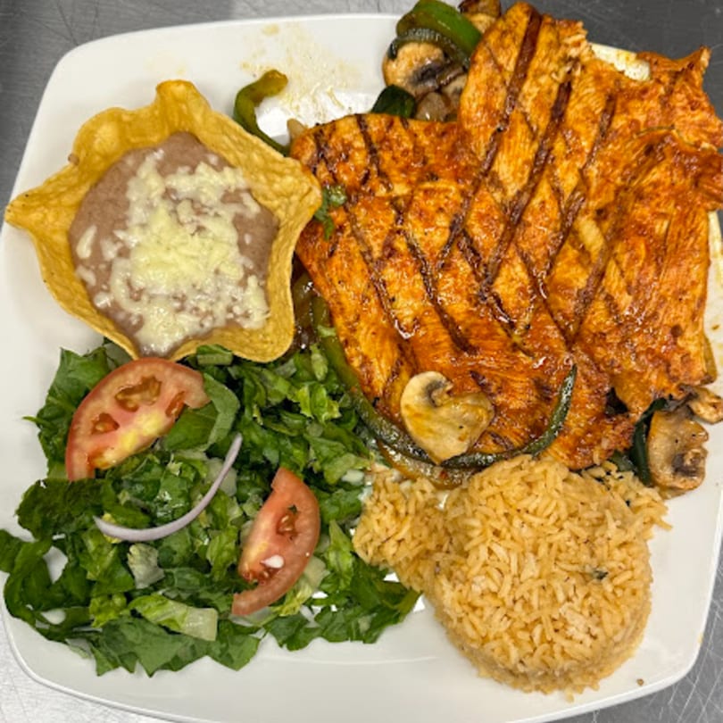 Grilled chicken with mushrooms, peppers, rice, refried beans in a tortilla bowl, and a side salad.