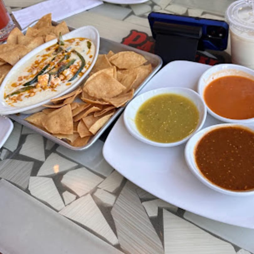 Padrino's Mexican restaurant table with queso fundido, tortilla chips, and three bowls of salsa.